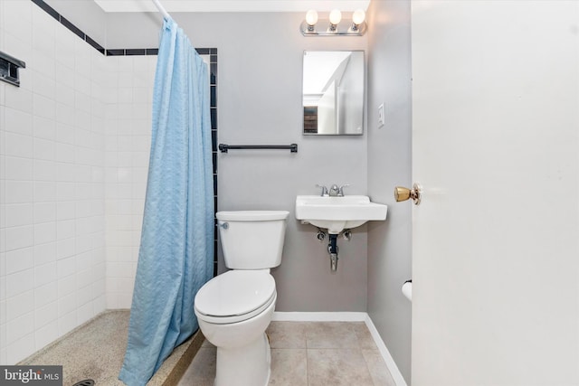 bathroom featuring tile patterned floors, baseboards, toilet, and a tile shower