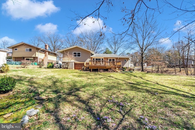 back of property with a deck, a yard, and a chimney