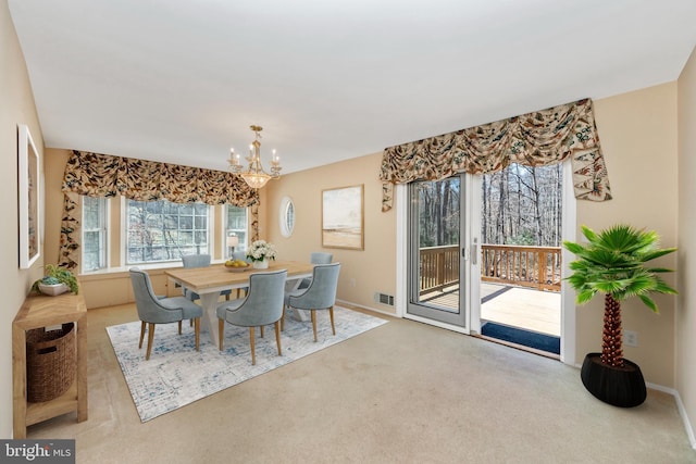 carpeted dining room featuring a notable chandelier, baseboards, and visible vents