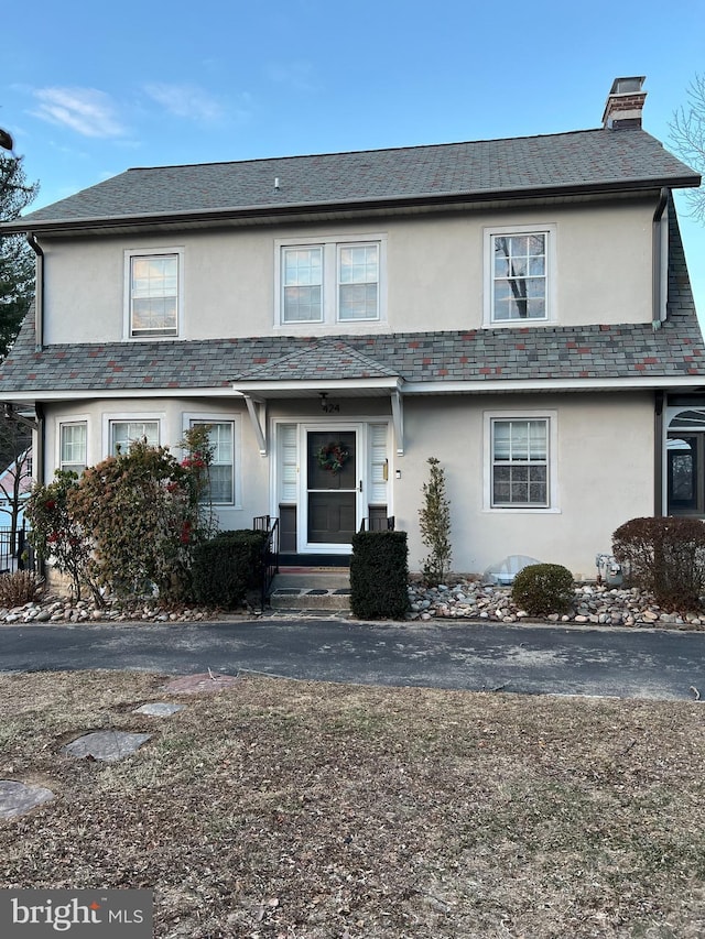 view of front of home with a high end roof, stucco siding, and a chimney