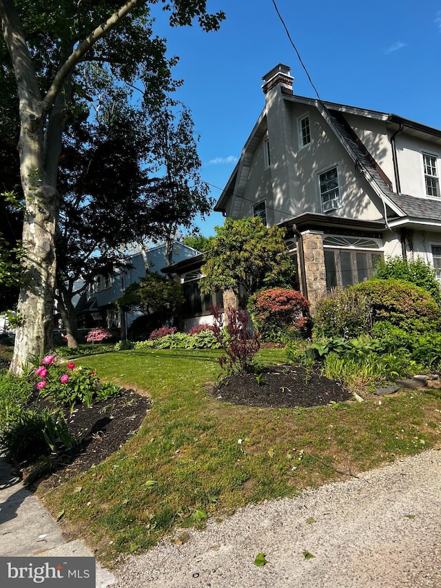 view of side of property with a lawn, a chimney, and stucco siding