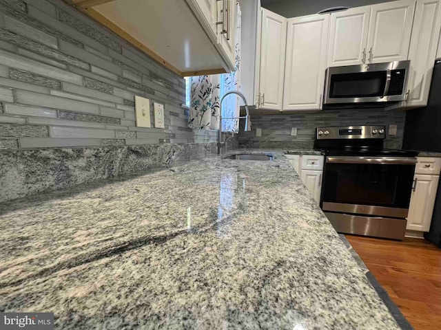 kitchen with backsplash, white cabinets, appliances with stainless steel finishes, and a sink