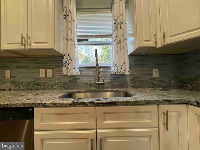 kitchen featuring a sink, dark stone countertops, tasteful backsplash, white cabinets, and dishwasher