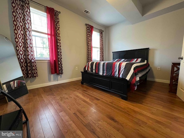 bedroom with visible vents, baseboards, and hardwood / wood-style flooring