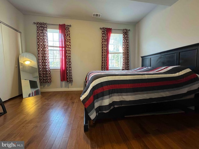 bedroom featuring visible vents, multiple windows, baseboards, and wood finished floors