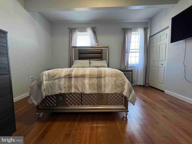 bedroom featuring multiple windows, wood finished floors, and baseboards