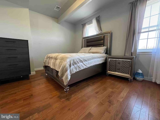 bedroom featuring beam ceiling, visible vents, baseboards, and wood-type flooring