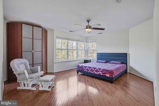 bedroom with hardwood / wood-style flooring, visible vents, and ceiling fan