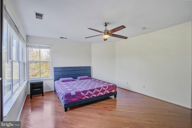 bedroom with light wood-style flooring, visible vents, and ceiling fan