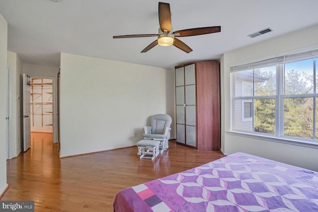 bedroom featuring multiple windows, wood finished floors, visible vents, and ceiling fan