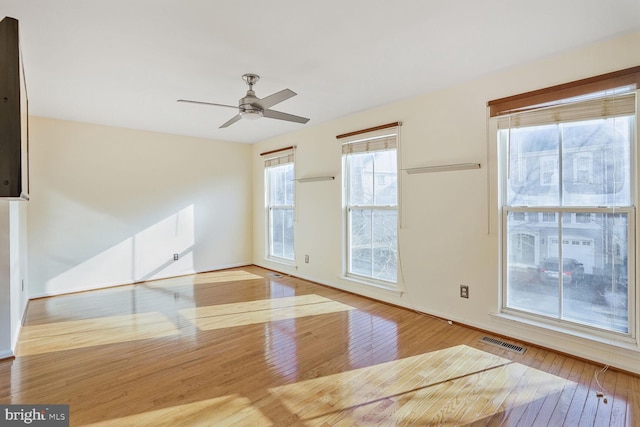 empty room featuring visible vents, ceiling fan, and hardwood / wood-style floors