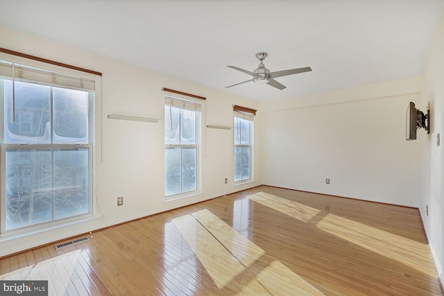 unfurnished room with ceiling fan, visible vents, baseboards, and hardwood / wood-style floors