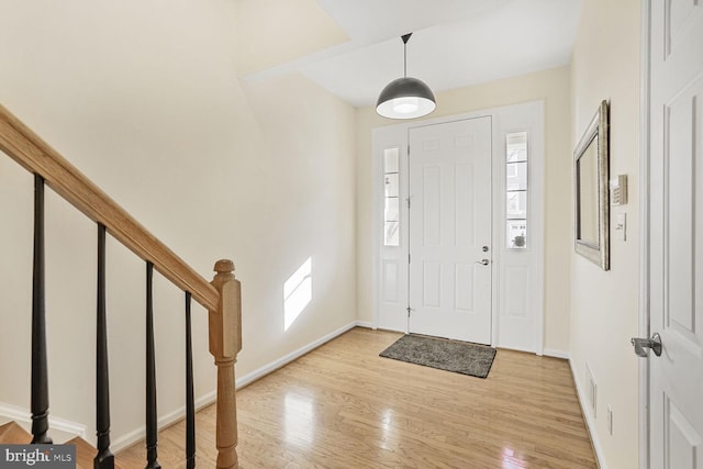 entryway with stairs, baseboards, and light wood-type flooring