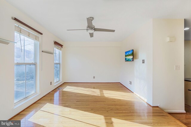 unfurnished room with ceiling fan, visible vents, baseboards, and wood finished floors