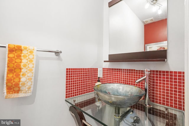 bathroom with a wainscoted wall, tile walls, visible vents, and a sink