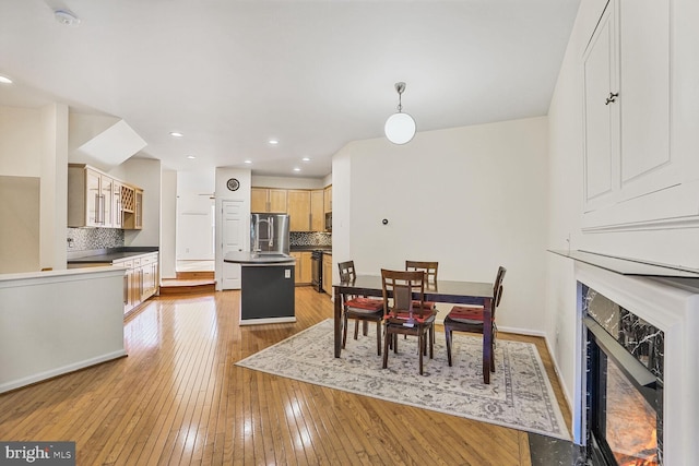 dining room with recessed lighting, light wood-type flooring, baseboards, and a fireplace