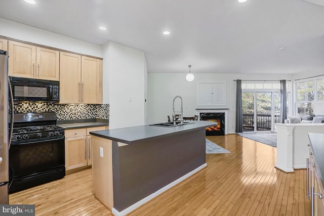 kitchen with light wood-style flooring, a sink, decorative backsplash, black appliances, and open floor plan