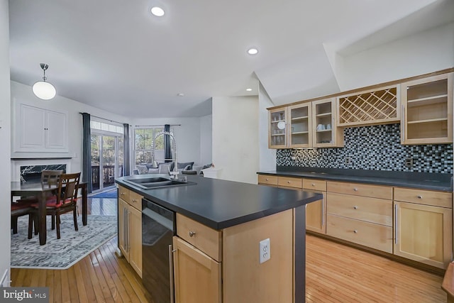 kitchen featuring dark countertops, tasteful backsplash, light brown cabinets, dishwasher, and light wood-style floors