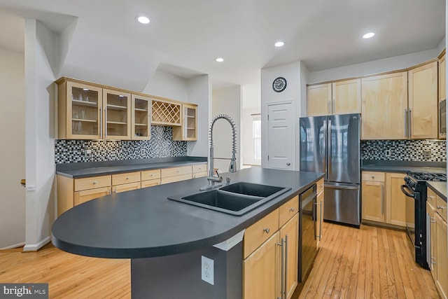 kitchen with dark countertops, stainless steel appliances, light brown cabinetry, and a sink