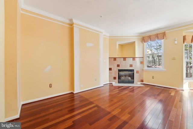 unfurnished living room with crown molding, baseboards, a tile fireplace, heating unit, and wood-type flooring