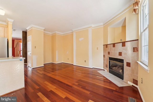 unfurnished living room with heating unit, visible vents, a fireplace, wood-type flooring, and crown molding