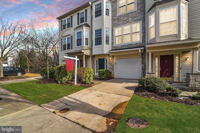 view of property featuring concrete driveway, an attached garage, and stone siding