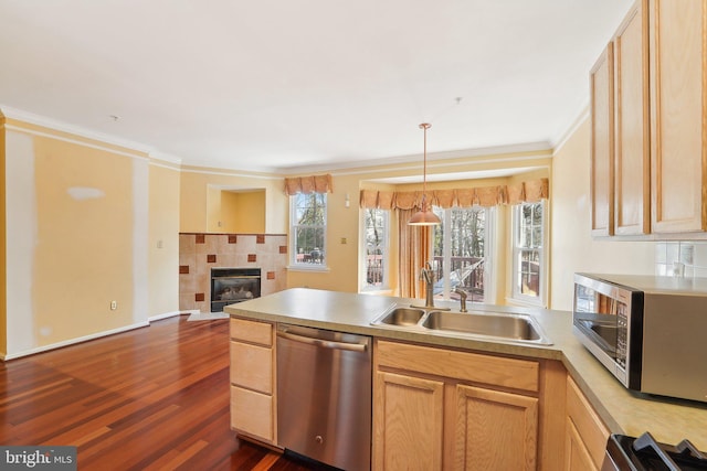 kitchen featuring a sink, stainless steel appliances, a peninsula, light countertops, and a tile fireplace