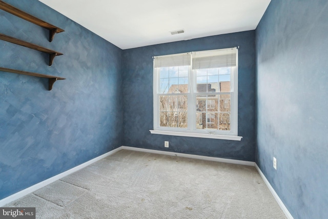 carpeted spare room with visible vents and baseboards