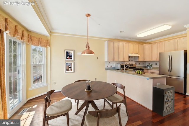 kitchen featuring visible vents, dark wood finished floors, a peninsula, light brown cabinetry, and appliances with stainless steel finishes