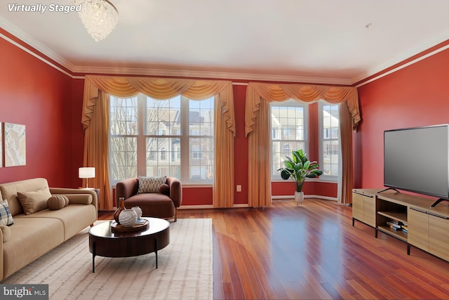 living room with crown molding, a notable chandelier, plenty of natural light, and wood finished floors