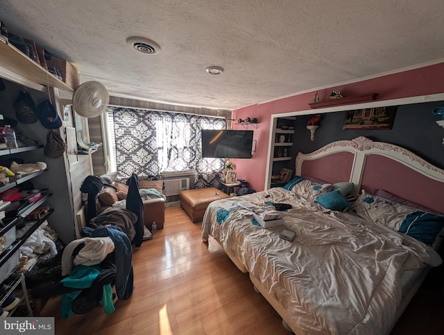 bedroom with light wood-style flooring, visible vents, and a textured ceiling