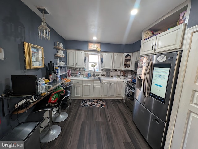 kitchen with dark wood finished floors, light countertops, decorative backsplash, stainless steel appliances, and white cabinetry