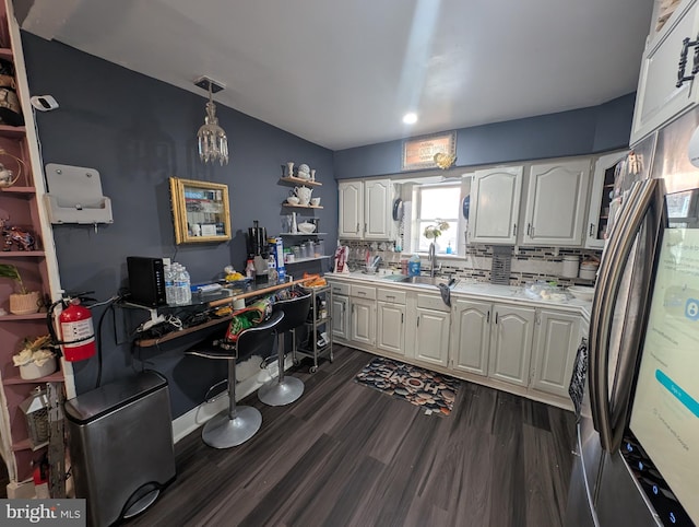 kitchen with white cabinetry, dark wood-type flooring, light countertops, and a sink