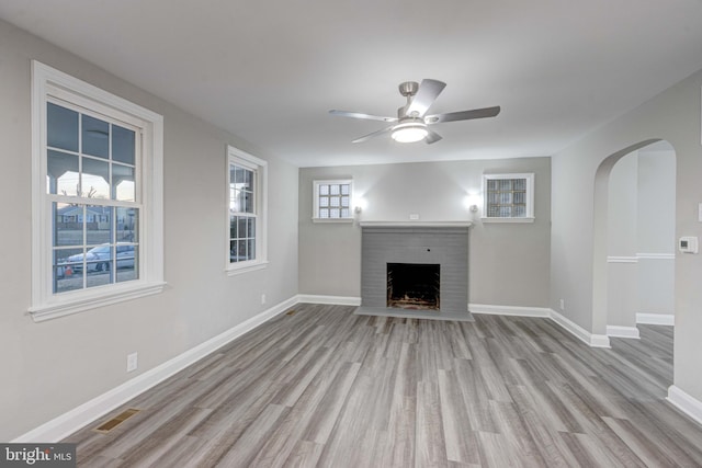 unfurnished living room featuring ceiling fan, baseboards, wood finished floors, and a fireplace