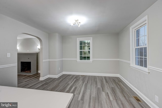 unfurnished living room featuring visible vents, baseboards, wood finished floors, and a fireplace