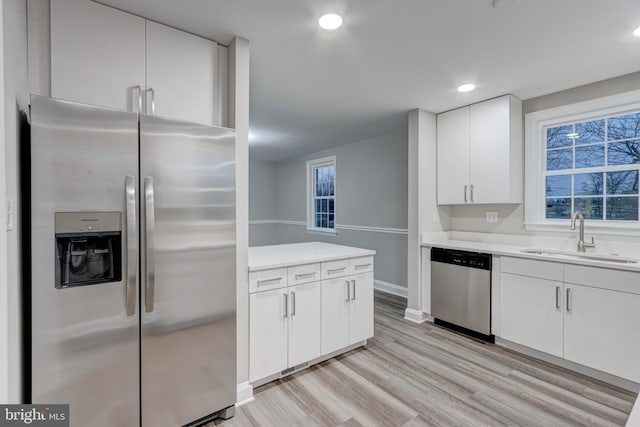 kitchen featuring light wood-style flooring, recessed lighting, a sink, stainless steel appliances, and white cabinets