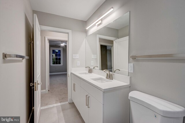 bathroom featuring a sink, baseboards, toilet, and double vanity