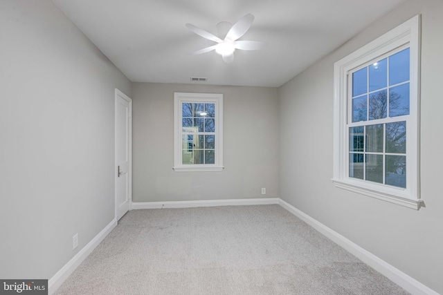 carpeted spare room with visible vents, a ceiling fan, and baseboards