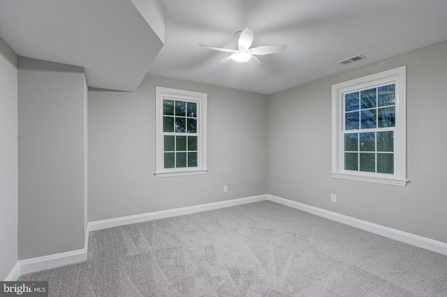 carpeted empty room with visible vents, a ceiling fan, and baseboards