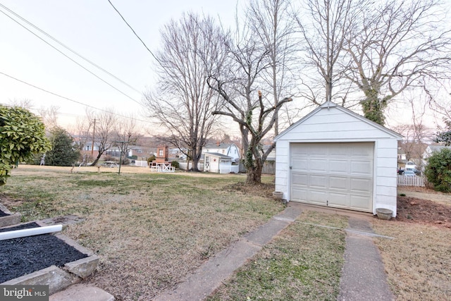 view of yard featuring a detached garage, an outbuilding, and fence