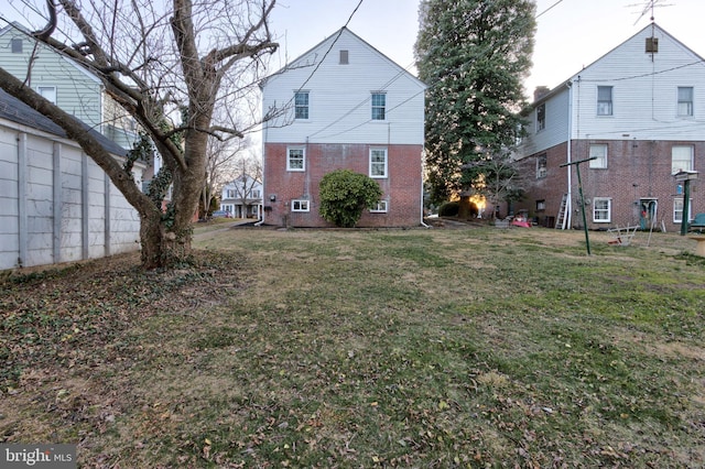 rear view of property featuring brick siding and a lawn