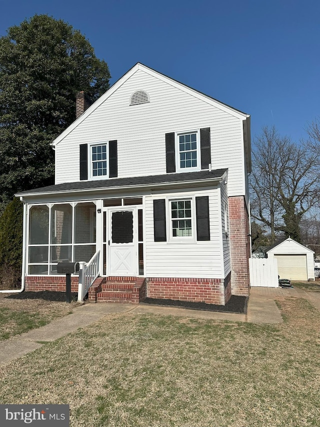 traditional-style home featuring a sunroom, a front yard, a chimney, an outdoor structure, and a garage