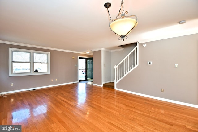 unfurnished room featuring visible vents, ornamental molding, stairway, light wood-style floors, and baseboards