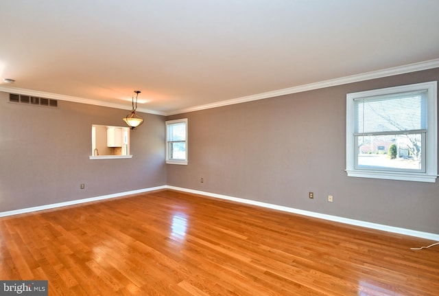 unfurnished room featuring visible vents, light wood-style flooring, crown molding, and baseboards