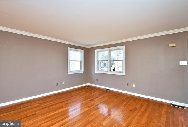 spare room featuring visible vents, baseboards, light wood-style floors, and ornamental molding