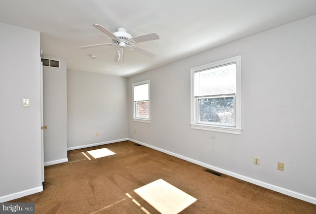 empty room with baseboards, visible vents, carpet floors, and ceiling fan