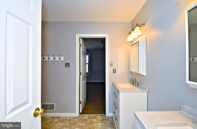 full bath featuring two vanities, baseboards, visible vents, and a sink