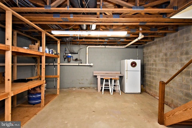 unfinished basement featuring freestanding refrigerator