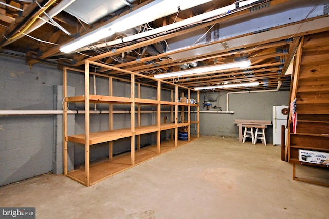 unfinished basement featuring freestanding refrigerator