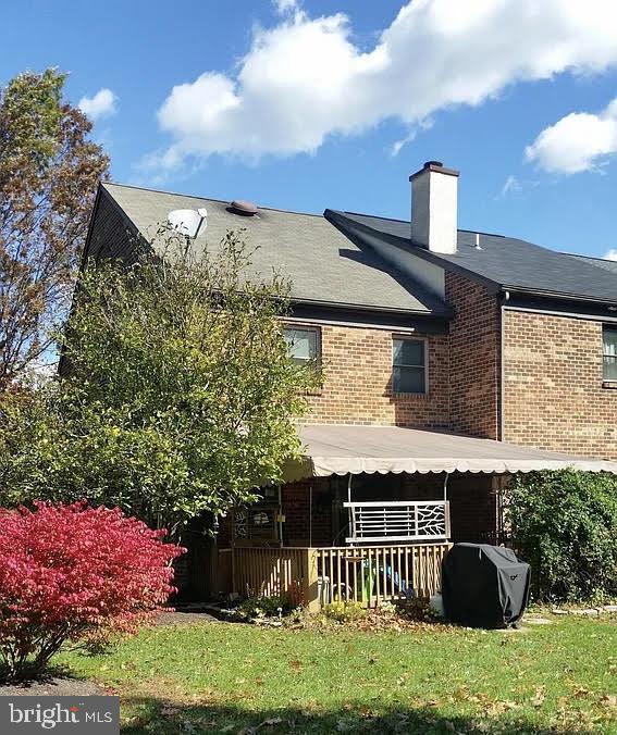 back of property with brick siding and a chimney